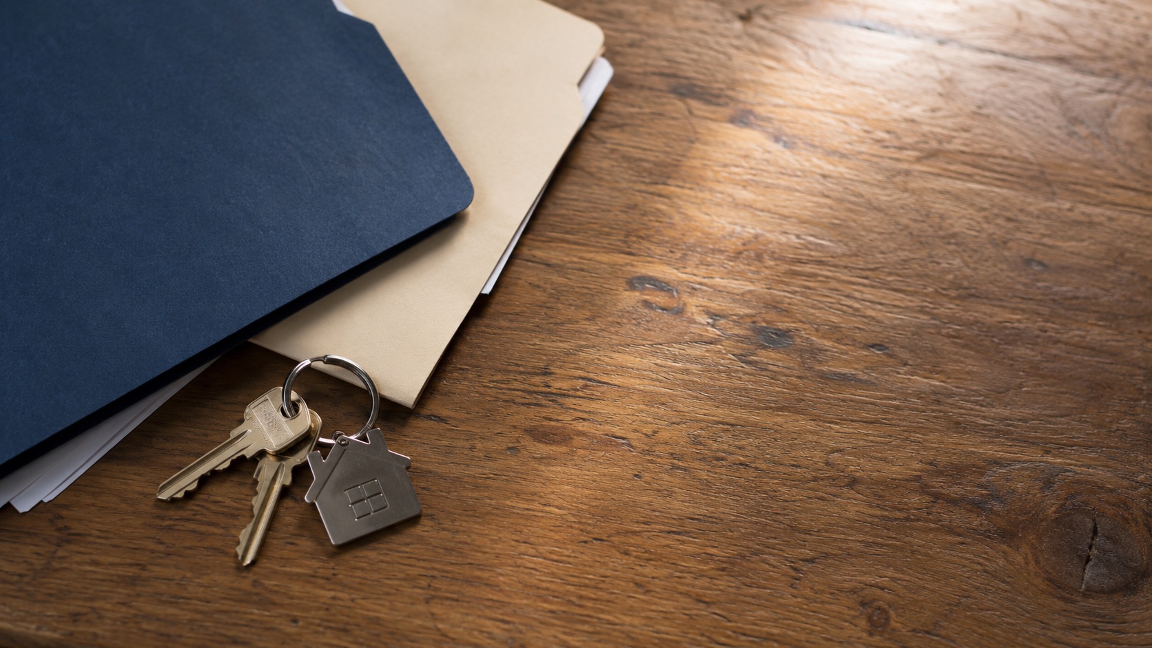 A single set of house keys placed between two closed unmarked household folders